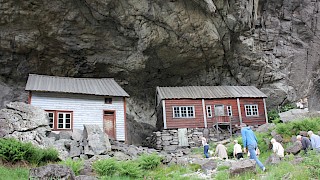 Et bilde utendørs med mennesker som vandrer rundt to hus