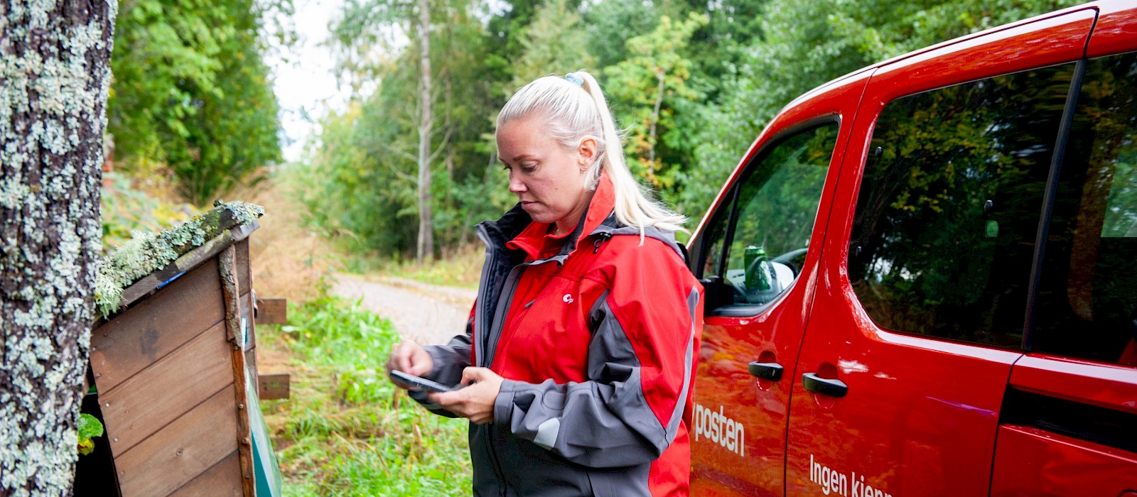 Bildet viser et postbud som leverer post i postkassen